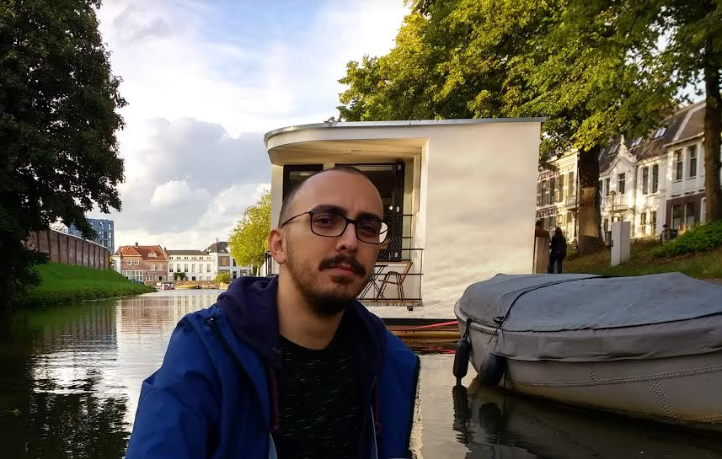 Male software developer enjoying a boat ride on the canal in his new home in the Netherlands.