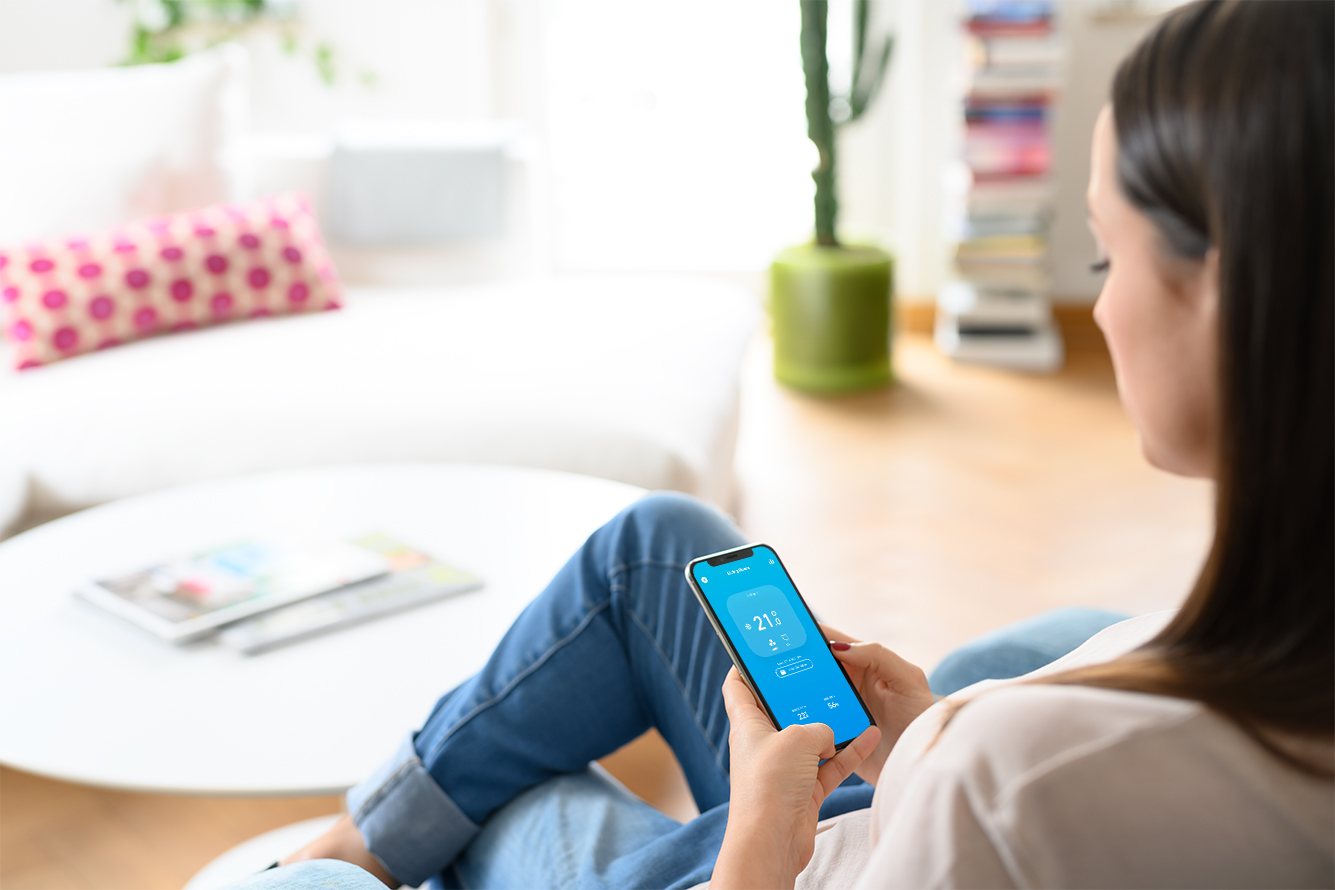 A woman uses her smartphone to control her tado° Smart Thermostat.